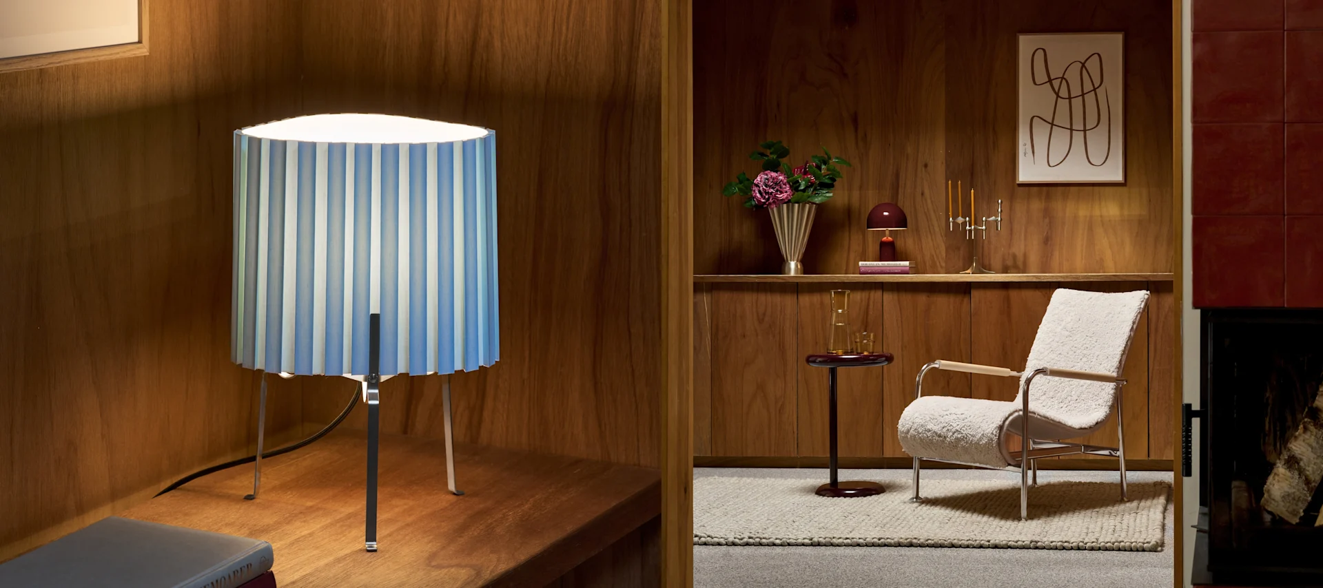A split image of two interior scenes. Left: a blue and white striped table lamp on a wooden shelf. Right: a living room with a furry armchair, a side table, shelf with decor, and a fireplace.
