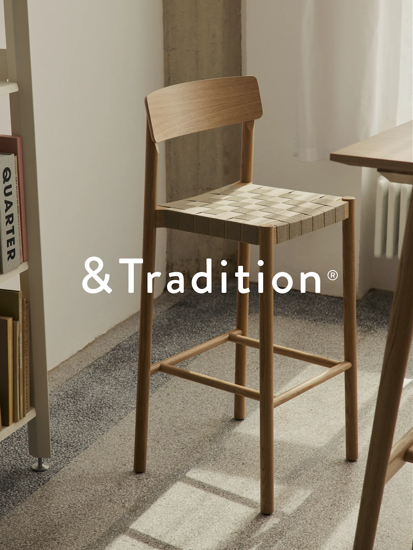 Tall light wood bar stool with a square woven seat, on a patterned floor.