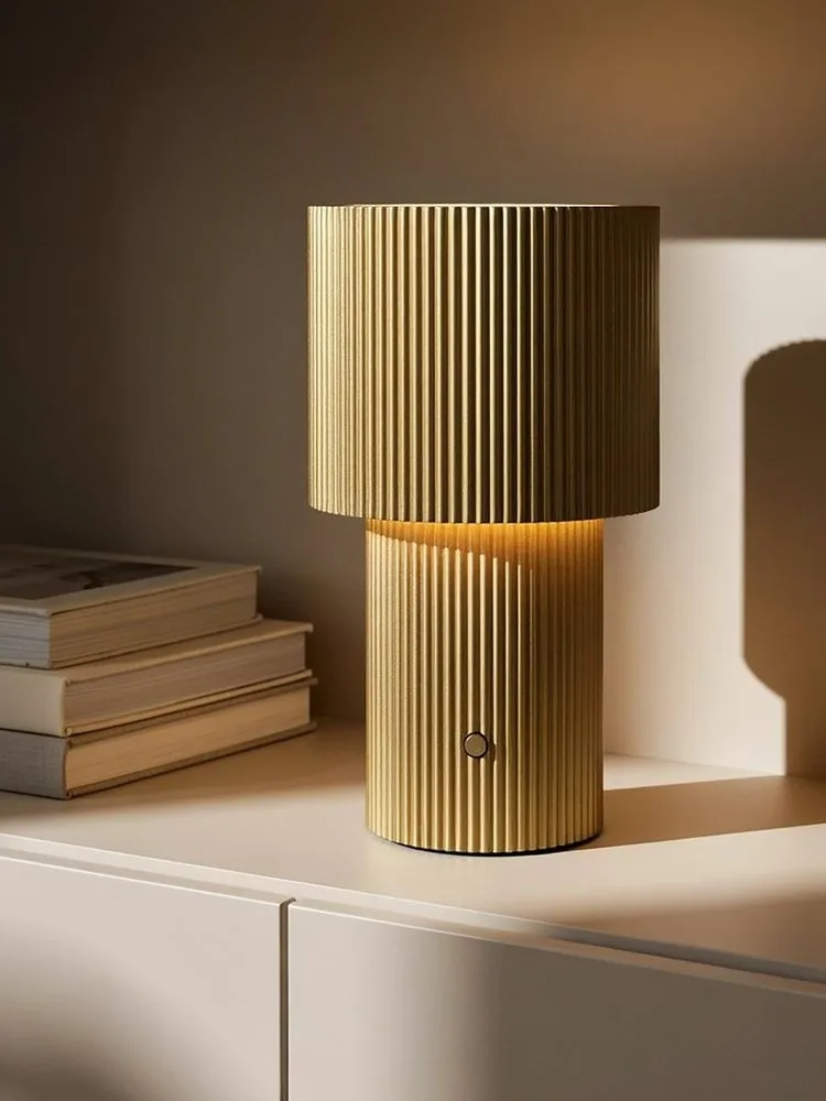 Gold ribbed table lamp, glowing, with a circular button on its base.