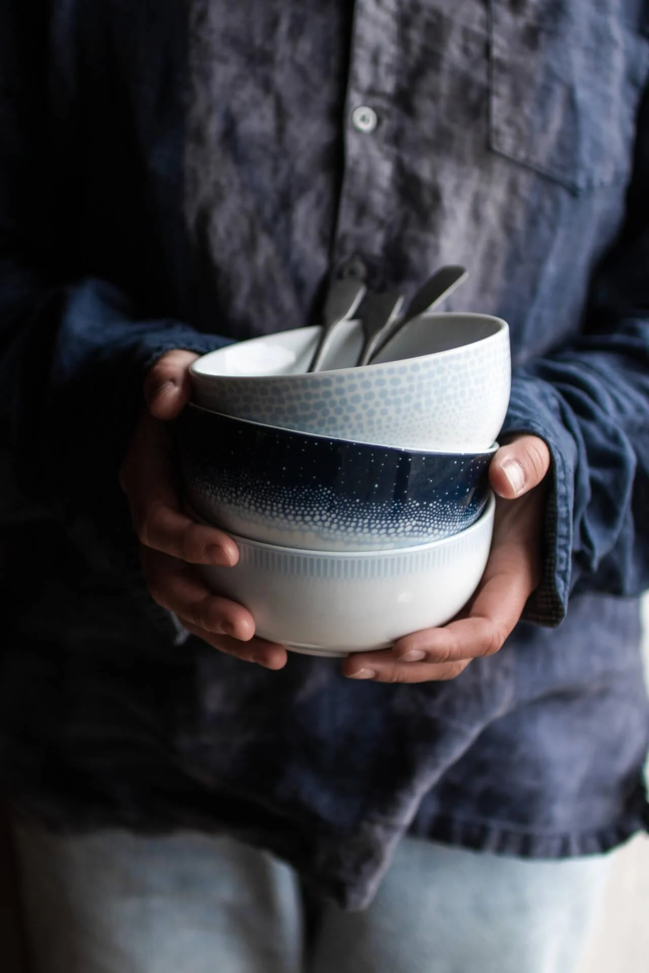 Here you see hands holding a stack of bowls from the Osean series from Wik & Walsøe.