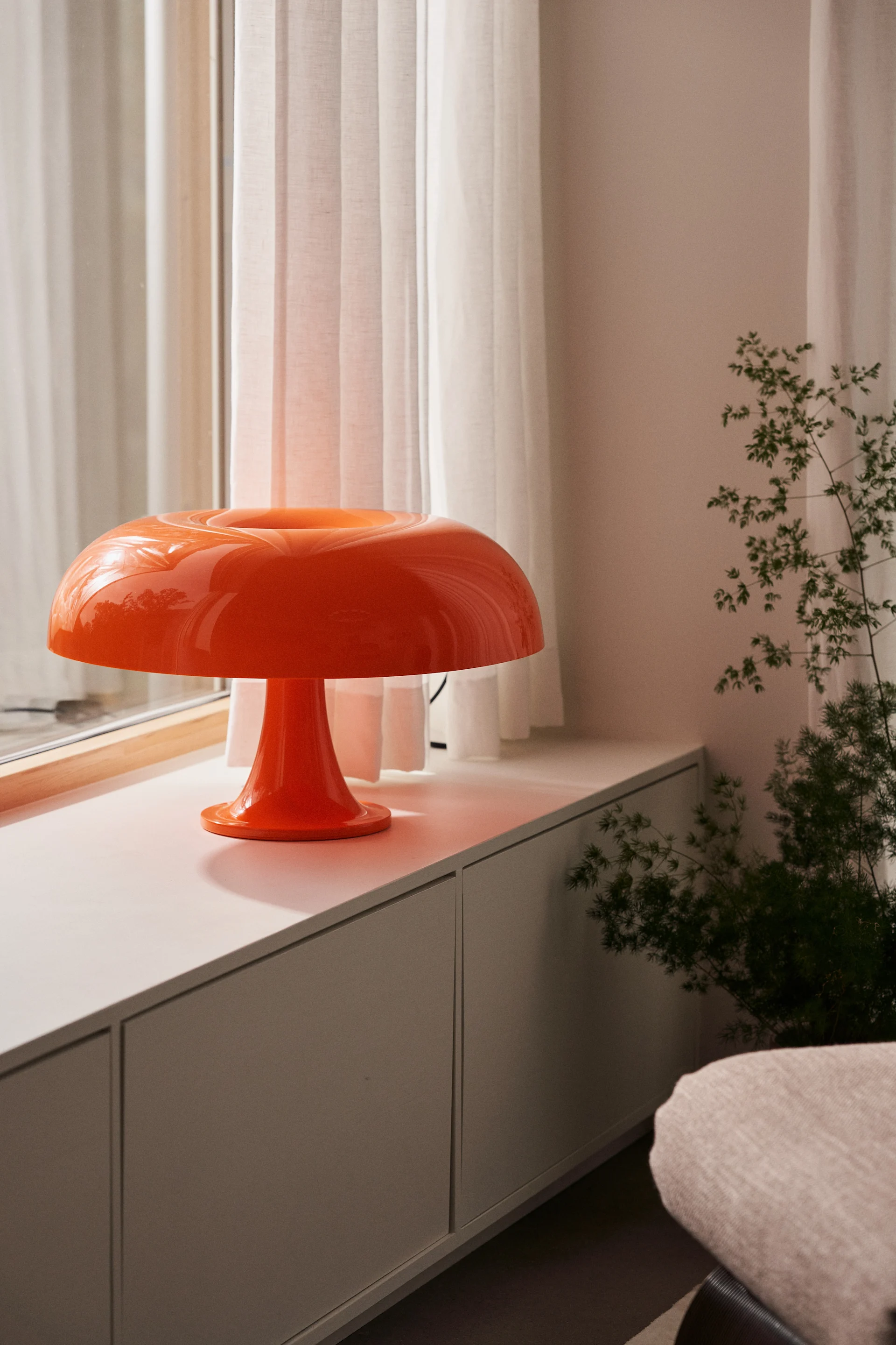 Ga voor kleur en laat je inspireren door de interieurtrends 2024 van dit jaar, hier Nesso van Artemide op de vensterbank in trendy oranje. 