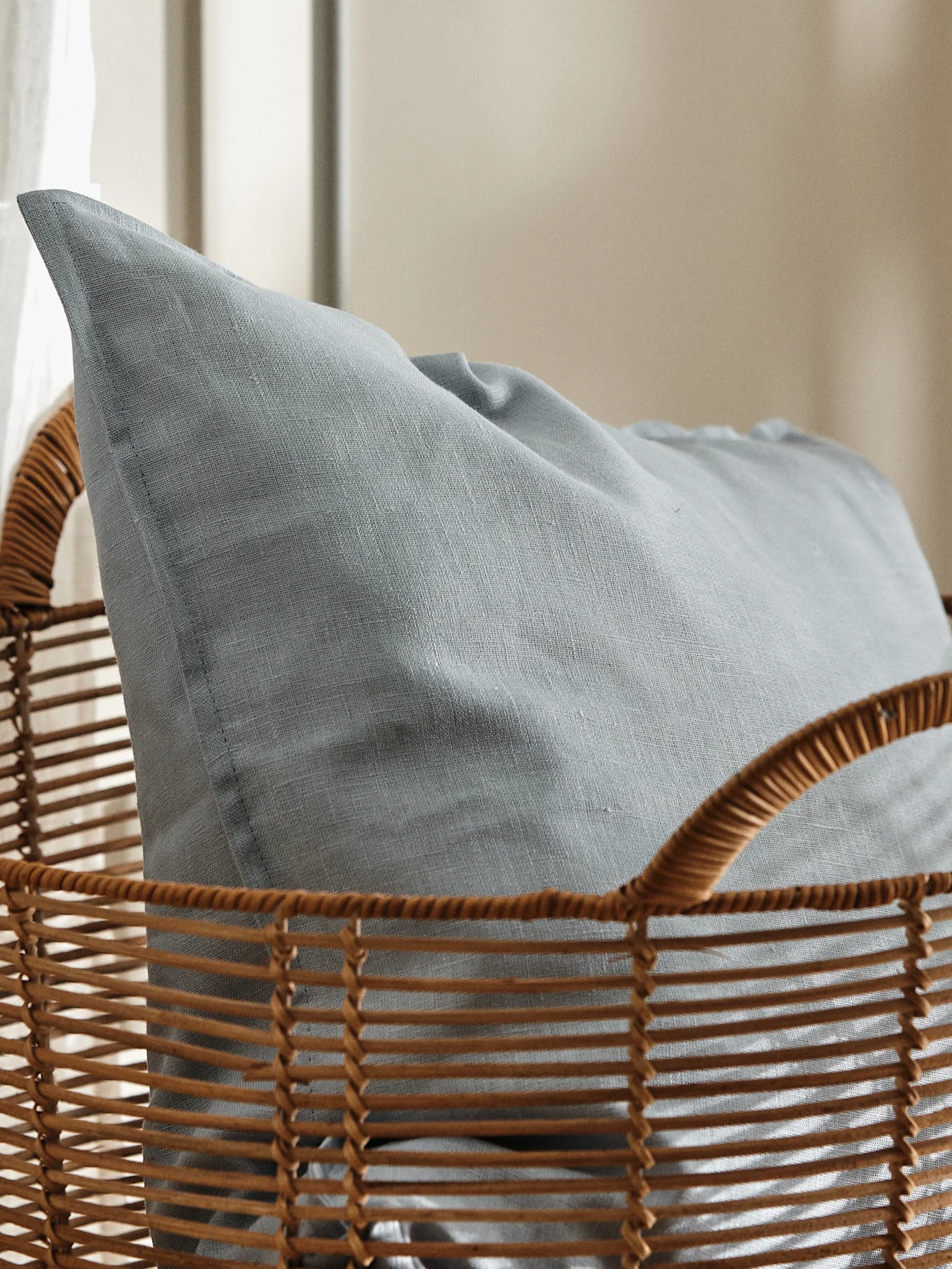 Light blue textured cushion nestled inside a brown woven wicker basket.