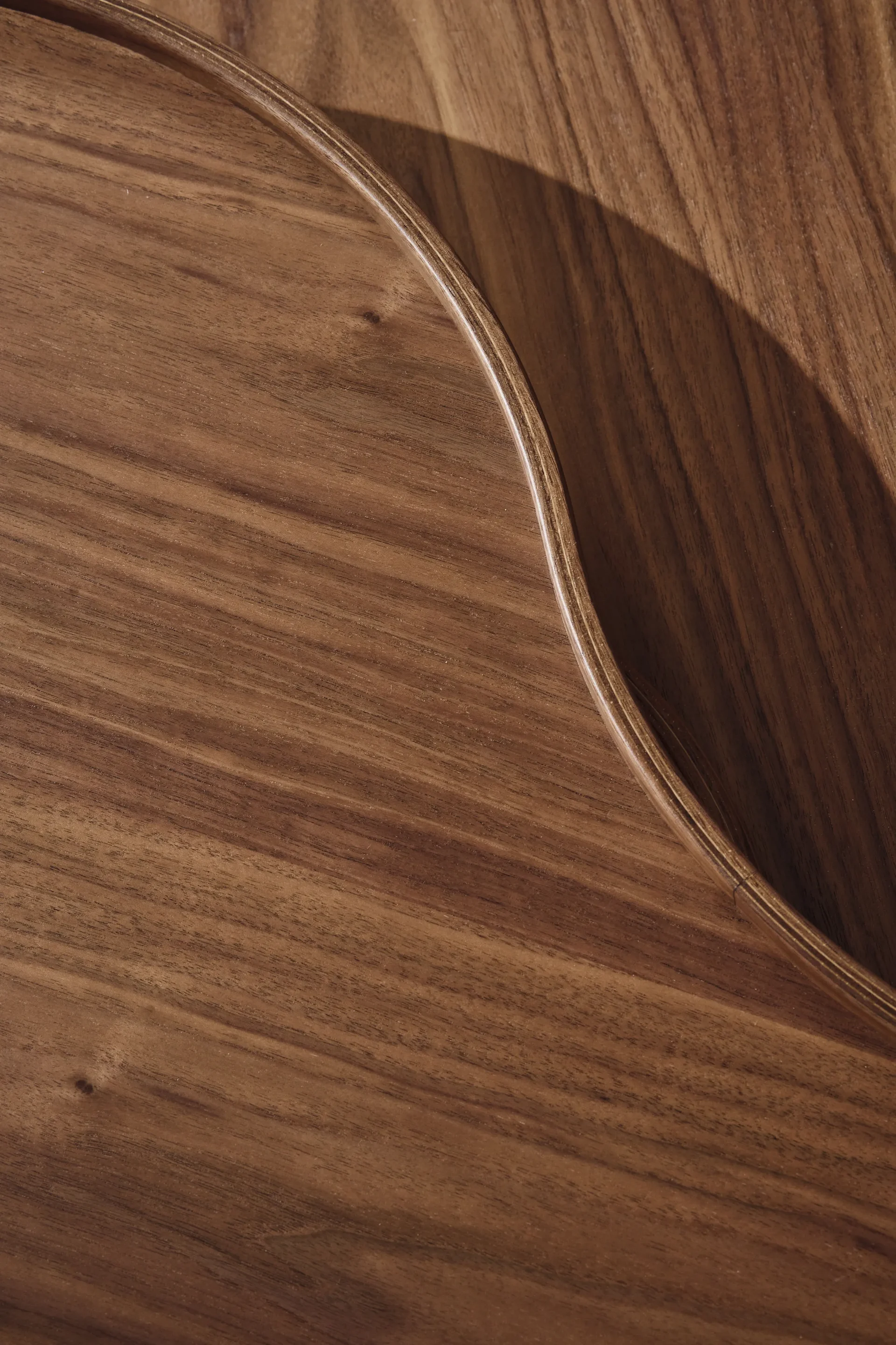 Close-up of a warm brown wooden surface with a curved, raised edge and visible grain.