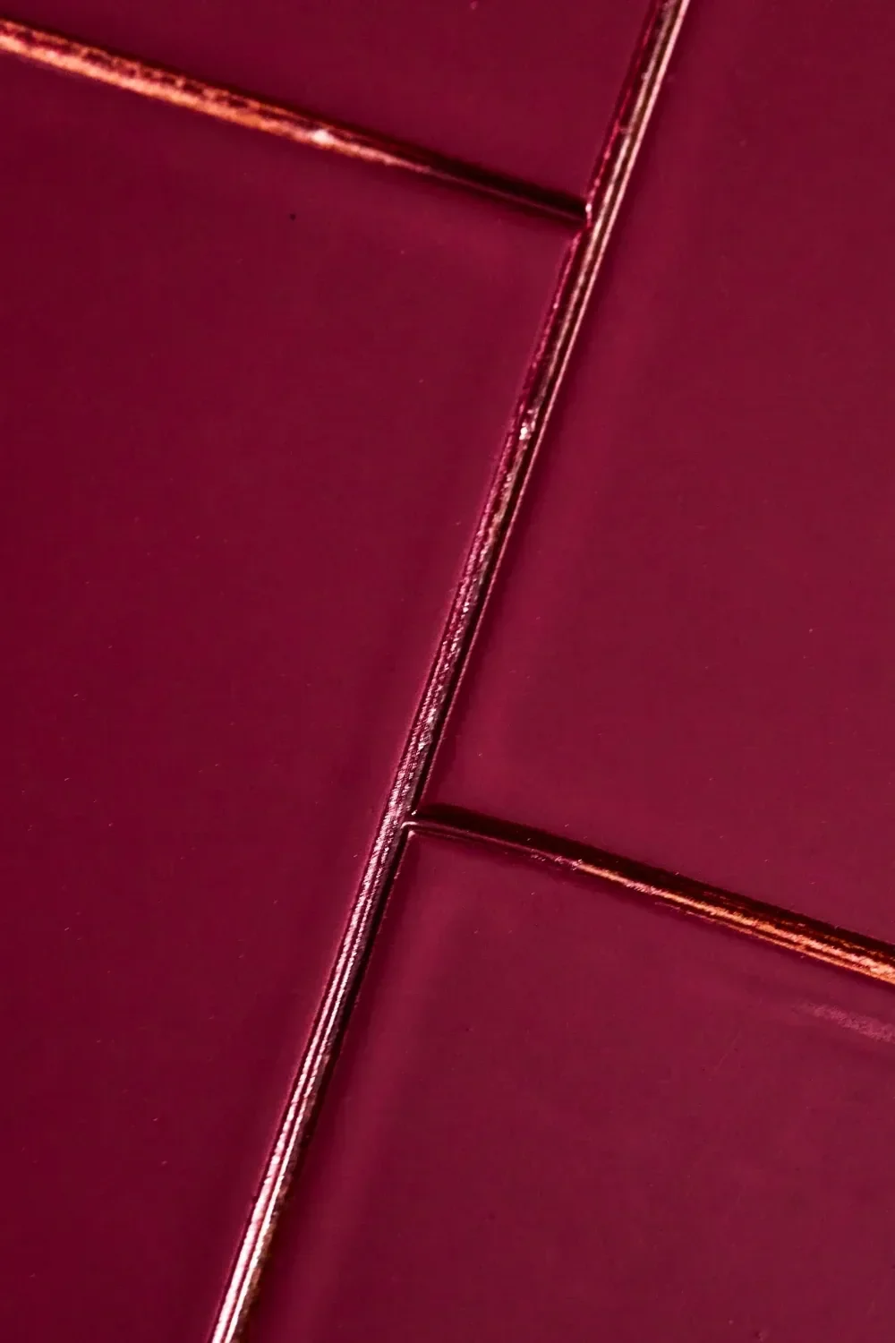 Glossy dark red tiles with metallic reddish-brown grout lines.