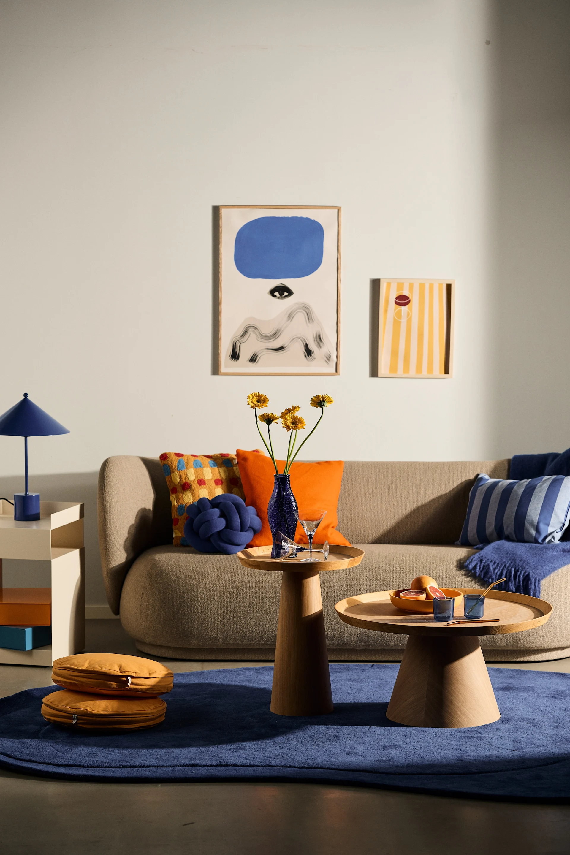 Decorate according to the Scandinavian interior design trends in 2024 and use lots of colour and patterns to mix & match. Here is a living room with blue. orange and yellow décor.