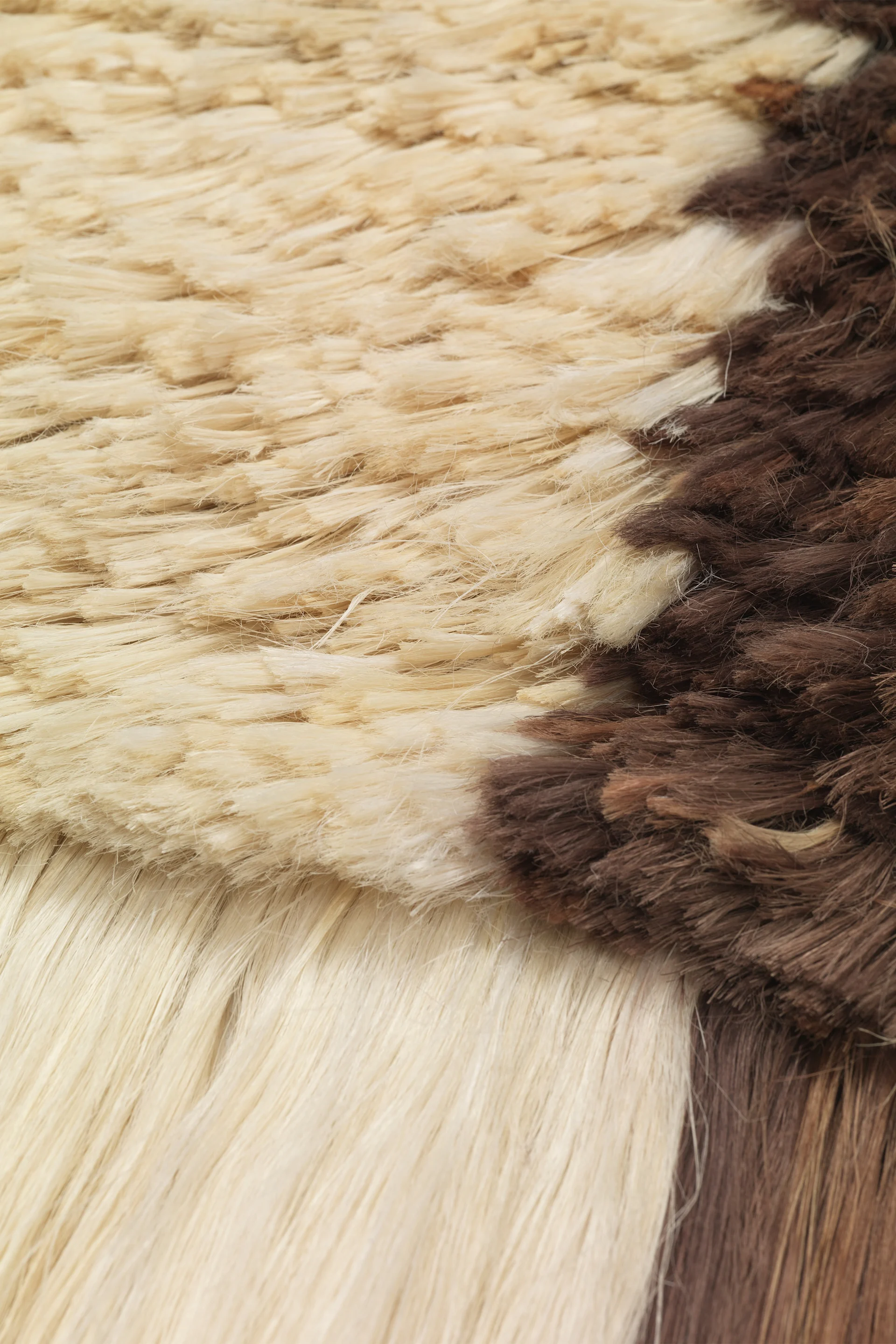 A close-up of a shaggy rug with light brown and dark brown sections.